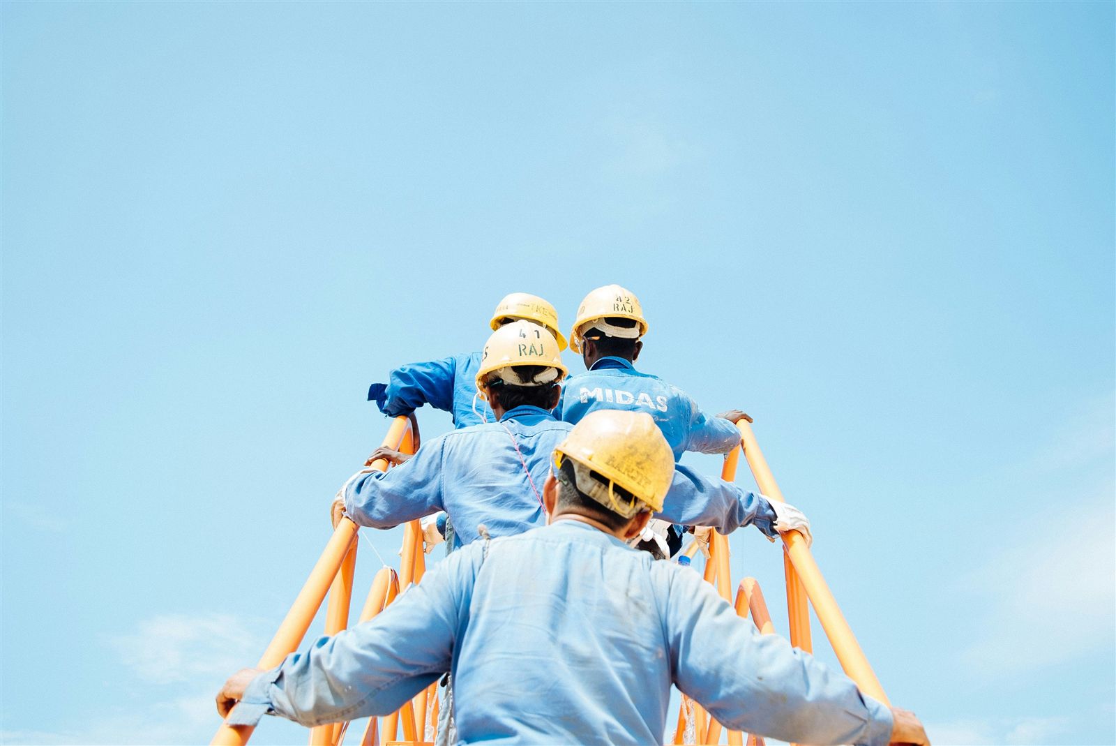 Team of workers in hard hats climbing together